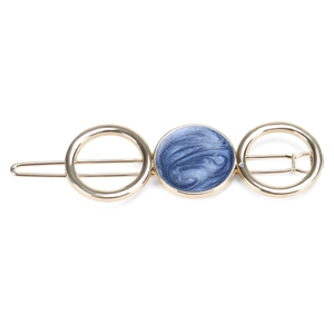 Detail of a gold alloy barrette featuring a navy marble inlay and hollow circular design