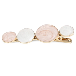 Détail d'une pince à cheveux dorée avec cercles en émail marbré rose et blanc poli