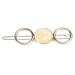 Detailed view of golden metal hair clip with cream marble resin circles and snap closure