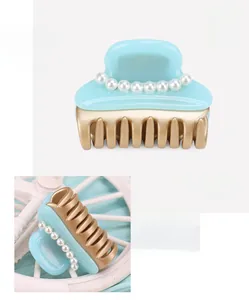 Detail of medium cellulose acetate hair claw clip with pearl accents in light blue and gold