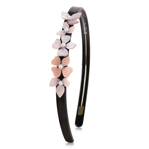 Detail of floral headband featuring pink resin petals and white pearls on black frame