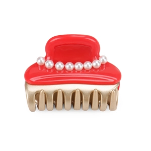 Detail of red acetate hair claw clip featuring row of pearls and gold finish claws