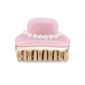 Detail showing pink acetate hair claw clip with elegant white pearls and gold metal teeth