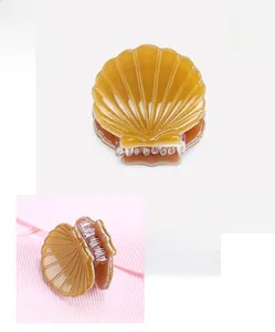 Mini shell hair claw detail in amber cellulose acetate with dimensions 2.4x2.1cm