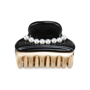 Detail showing elegant black acetate hair claw clip with white pearls and gold teeth