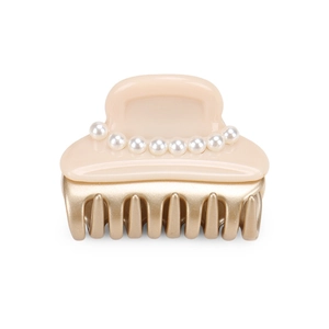 Close-up of cream beige hair claw clip with nine white pearls and golden metallic teeth