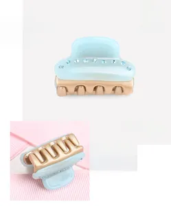 Detail view of mini acetate hair claw with rhinestones and golden base in light blue