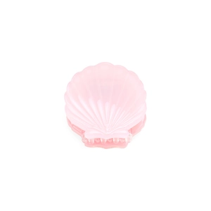 Close-up of a small shell-shaped acetate hair claw clip in translucent pink finish