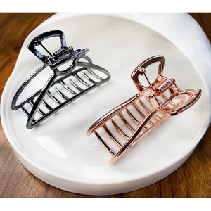 Elegant hollow alloy hair claws in gunmetal and rose gold on a white ceramic tray