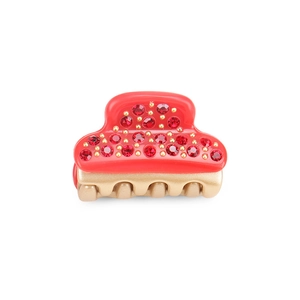 Detail shot of a small red acetate hair claw clip with sparkling rhinestones and gold base