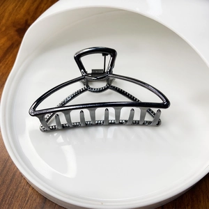 Close-up of a glossy black moon-shaped alloy hair claw clip with strong metal spring