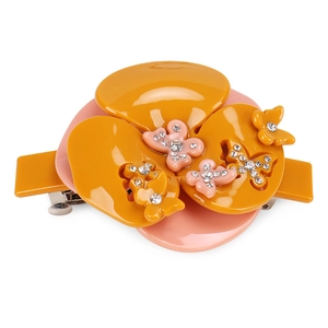 Détail d'une pince à cheveux en acétate avec fleur de camélia jaune et papillon strass