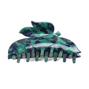 Detail of leaf-shaped acetate hair claw featuring marble texture in deep green and ink blue