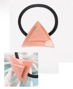 Macro detail of coral pink cellulose acetate triangular hair tie showing texture and elastic cord