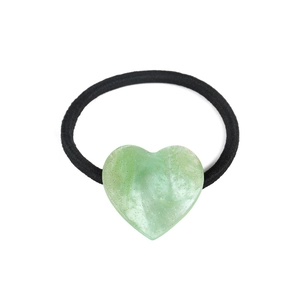 Detail of light green acetate heart hair tie with gold glitter and marble texture