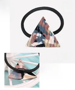 Detail view showing a geometric acetate triangle hair tie with marble texture and dimensions