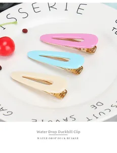 Close-up of three water drop hair clips in pink, blue, and yellow on a white plate