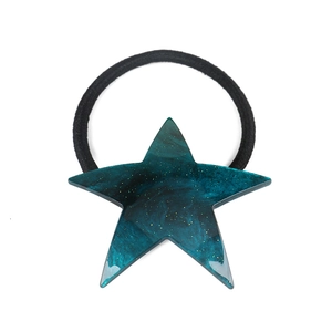 Close-up of a dark teal marble star hair tie with gold glitter and black elastic band