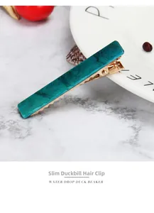 Detailed close-up of a long green marble acetate hair clip with a golden alloy base