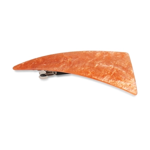 Macro detail of orange marble texture hair clip with glitter and silver metal base
