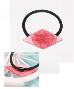 Detail view of pink diamond-shaped acrylic hair tie with sparkles and black elastic band