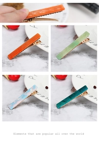 Detailed macro view of four colorful rectangular acetate hair clips with gold metal base