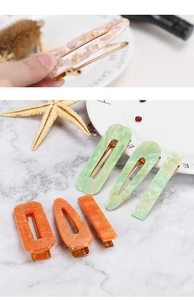 Detail view of colorful marbled acetate hair clips with golden metal duckbill base