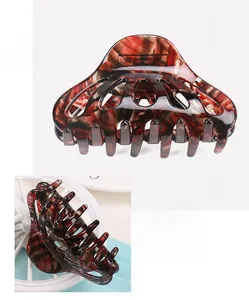 Detail view of cellulose acetate hair claw clip with red marble pattern and 19.3g weight