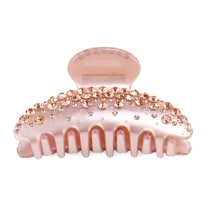 Détail de la pince à cheveux en acétate rose avec strass brillants sur fond blanc neutre