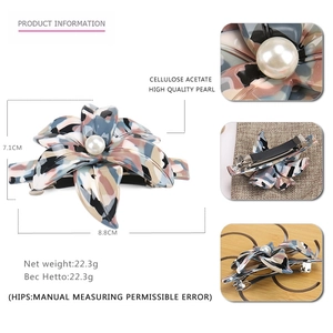Detail view of 7.1cm acetate flower hair clip with large pearl center and spring clip