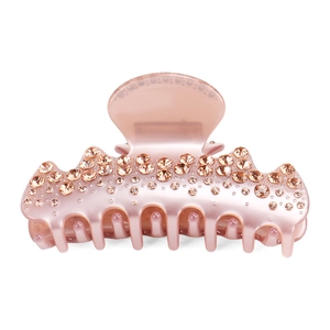Detailed macro view of pearlescent pink hair claw clip with champagne rhinestones