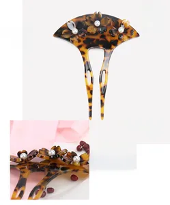 Detail of tortoise shell acetate hairpin with floral pattern and white pearl accents