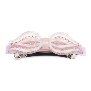 Détail d'une barrette à cheveux nœud rose en acétate avec des strass et clip métal