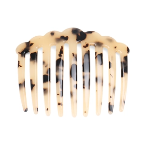 Detail view of acetate hair comb featuring vintage tortoiseshell pattern on white background