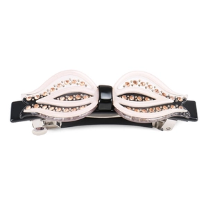 Vue détaillée d'une barrette noeud en acétate rose avec strass champagne et clip en métal