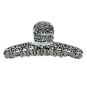 Detail of large acetate hair claw clip featuring black and white spotted leopard pattern
