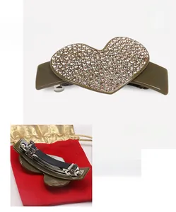 Detailed macro view showing the rhinestone heart design and metal spring clip hair accessory