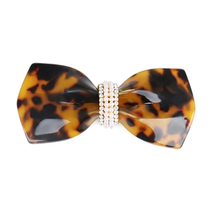 Detailed macro of tortoise shell bow hair clip with pearl and rhinestone accents