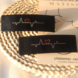Détail des pinces en acétate avec strass en forme d'électrocardiogramme et cœur rouge