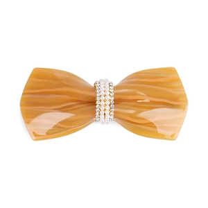 Detailed close-up of yellow marble acetate bow clip with pearl and rhinestone inlay