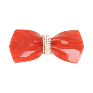 Detail of red acetate bow hair clip with luxury pearl and rhinestone center decoration