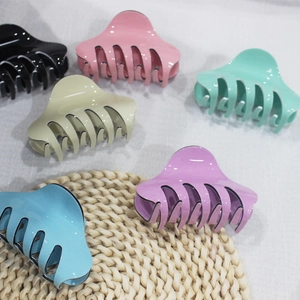 Dettaglio macro di grandi mollettoni per capelli macaron con design multi-dente e bordo nero