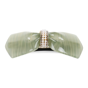 Detail of green acetate bow hair clip with white pearls and small rhinestones embellishment