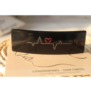 Détail d'une pince à cheveux noire en acétate avec motif d'électrocardiogramme et cœur