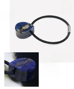 Détail du pendentif goutte en acétate marbré bleu sur un élastique à cheveux noir