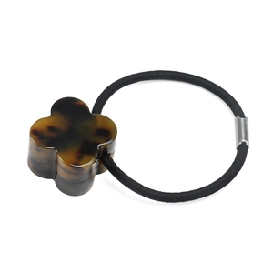Macro detail of tortoiseshell clover charm on high-elastic black hair tie for women