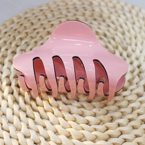 Vista macro del mollettone per capelli in acrilico rosa con finitura lucida e denti lisci