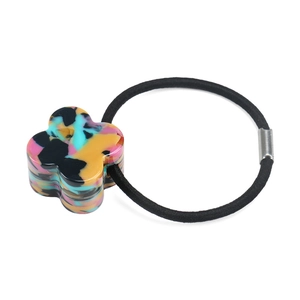 Detailed macro view of an acetate clover charm with colorful camo patterns on a black hair tie