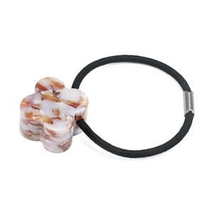 Detailed close-up of clover-shaped acetate hair tie with elegant marble texture and elastic band