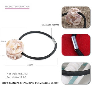 Detail view of acetate hair tie with marble texture cylinder and dimensions of 1.6cm by 2.5cm